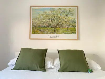 a painting above a bed with two green pillows at Gades Natura Victoria Beach in Cádiz