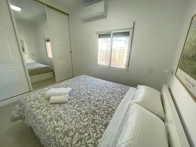 a white bedroom with a bed and a mirror at Gades Natura Victoria Beach in Cádiz