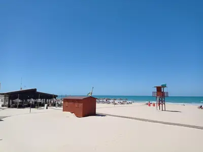 a sandy beach with a lifeguard tower and the ocean at Gades Natura Victoria Beach in Cádiz