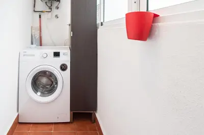 a washing machine in a bathroom with a red bucket at Apartamento El Anteojo de Cádiz in Cádiz