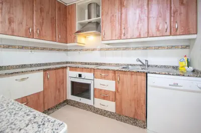 a kitchen with wooden cabinets and a sink at Apartamento El Anteojo de Cádiz in Cádiz