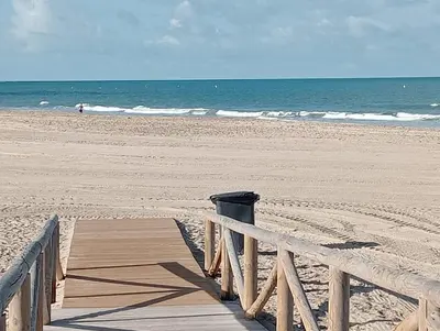 a trash can on a wooden boardwalk on the beach at Apartamento Mar II in San Fernando