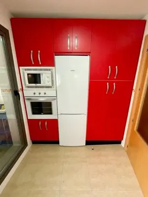 a kitchen with red cabinets and a white refrigerator at GATU PREMIUM Marismas, terraza, parking, piscina común y aire acc , 