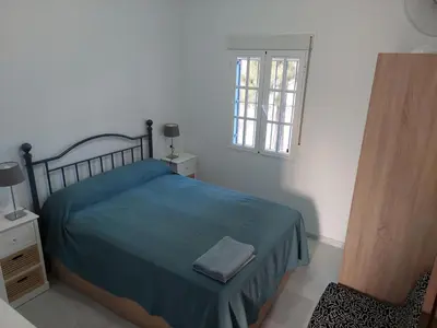 a bedroom with a bed with a blue blanket and a window at Villa Puerto Santa María in El Puerto de Santa María