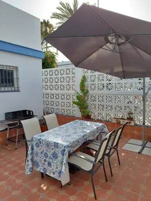 a table and chairs with an umbrella on a patio at Villa Puerto Santa María in El Puerto de Santa María