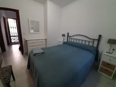 a bedroom with a bed and a dresser and a window at Villa Puerto Santa María in El Puerto de Santa María