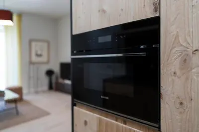 a black microwave on a wooden wall in a living room at Alma Playa la Caleta Grupo AC Gestion in Cádiz