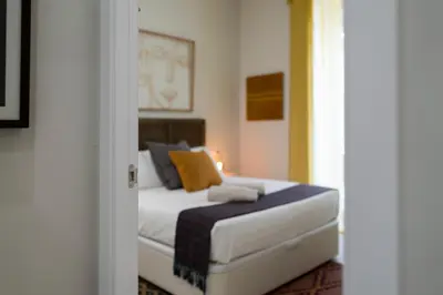 a bedroom with a bed with yellow and blue pillows at Alma Playa la Caleta Grupo AC Gestion in Cádiz