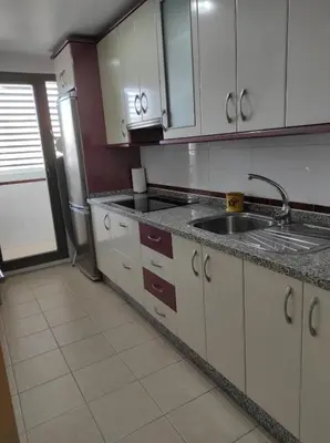 a kitchen with white cabinets and a tile floor at EL ATICO DE MARIA con garaje, piscina y terraza in El Puerto de Santa María