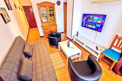 a living room with a couch and a tv at Ocean View Beach Apartment with Pool & Balconies in El Puerto de Santa María