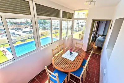a table and chairs in a room with windows at Ocean View Beach Apartment with Pool & Balconies in El Puerto de Santa María