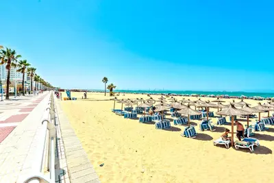 a beach with chairs and umbrellas and the ocean at Ocean View Beach Apartment with Pool & Balconies in El Puerto de Santa María