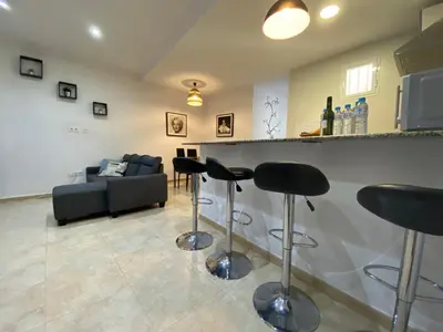 a living room with a bar with stools and a couch at Alojamiento Cazón, Jerez Centro in Jerez de la Frontera