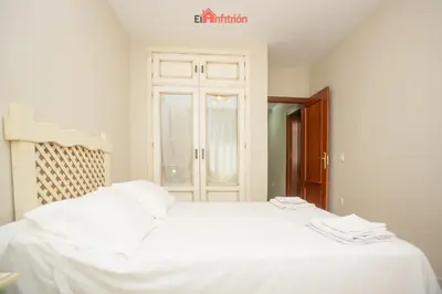 a white bed with white sheets in a room at El Anfitrión - Dúplex Doña Ana in Sanlúcar de Barrameda