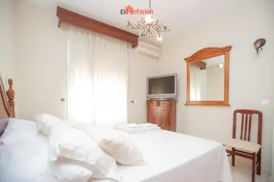 a white bedroom with a bed and a mirror at El Anfitrión - Dúplex Doña Ana in Sanlúcar de Barrameda