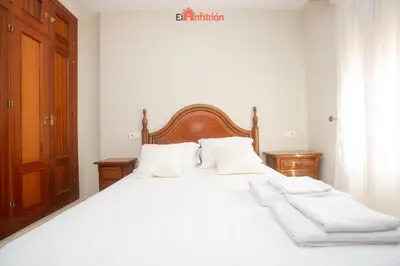a bedroom with a large white bed with white pillows at El Anfitrión - Dúplex Doña Ana in Sanlúcar de Barrameda