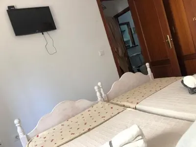 a bedroom with a bed with a tv on the wall at ACOGEDOR APARTAMENTO EN SANLUCAR DE BARRAMEDA in Sanlúcar de Barrameda