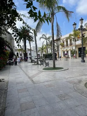 a plaza with palm trees and benches and buildings at CASA RAUSER in Chipiona