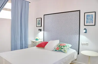 a bedroom with a white bed and a mirror at Chalet Isla Papua in Chiclana de la Frontera