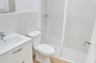 a white bathroom with a toilet and a shower at Chalet Isla Papua in Chiclana de la Frontera