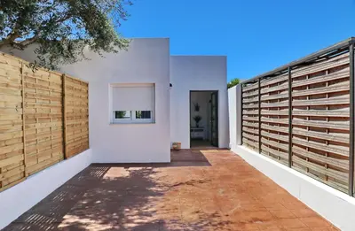 a backyard with two chairs and a table and a fence at Chalet Isla Papua in Chiclana de la Frontera