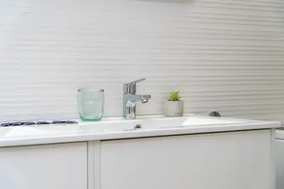a bathroom sink with a glass on top of it at Suit 42 Playa y Ascensor Grupo AC Gestion in Cádiz