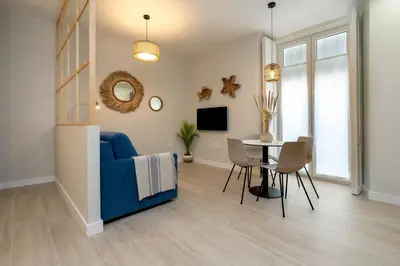 a living room with a blue couch and a table at Suit 42 Playa y Ascensor Grupo AC Gestion in Cádiz