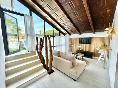 a living room with a white couch and a staircase at VILLA PIMIENTA, Chalet de lujo a 100 metros del mar in Chiclana de la Frontera
