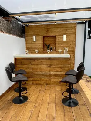 a bar with two chairs and a counter with wine glasses at VILLA PIMIENTA, Chalet de lujo a 100 metros del mar in Chiclana de la Frontera