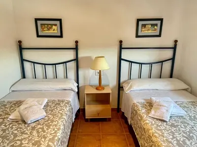 two beds in a room with a lamp on a night stand at Ático Amaranta in Chiclana de la Frontera