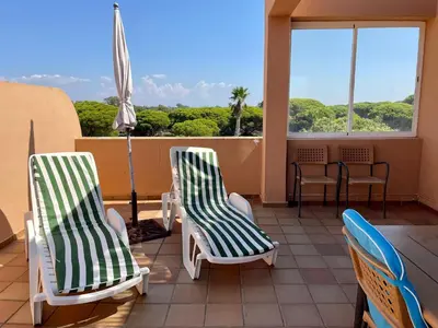 two chairs and an umbrella on a balcony at Ático Amaranta in Chiclana de la Frontera