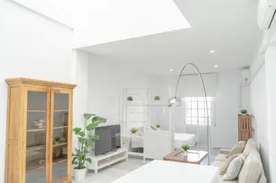 a white living room with a couch and a tv at LOFT SÚPER LUMINOSO EN EL CENTRO DEL PUERTO DE SANTA MARÍA. in El Puerto de Santa María