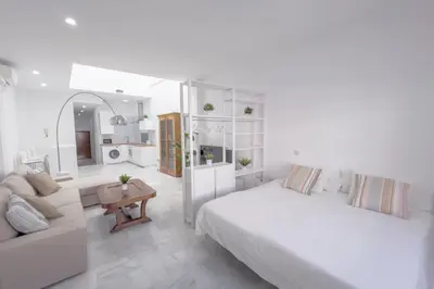 a white bedroom with a bed and a living room at LOFT SÚPER LUMINOSO EN EL CENTRO DEL PUERTO DE SANTA MARÍA. in El Puerto de Santa María
