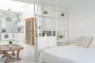 a white bedroom with a bed and a table at LOFT SÚPER LUMINOSO EN EL CENTRO DEL PUERTO DE SANTA MARÍA. in El Puerto de Santa María