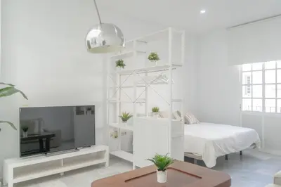 a white room with a bed and a tv at LOFT SÚPER LUMINOSO EN EL CENTRO DEL PUERTO DE SANTA MARÍA. in El Puerto de Santa María