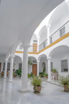 a large white building with potted plants in a courtyard at LOFT SÚPER LUMINOSO EN EL CENTRO DEL PUERTO DE SANTA MARÍA. in El Puerto de Santa María