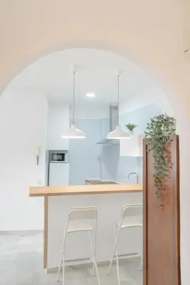 a kitchen with white walls and a counter with stools at Apartamento completamente nuevo en pleno centro del Puerto in El Puerto de Santa María