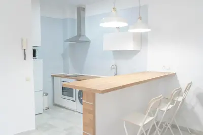 a kitchen with white cabinets and a counter with chairs at Apartamento completamente nuevo en pleno centro del Puerto in El Puerto de Santa María