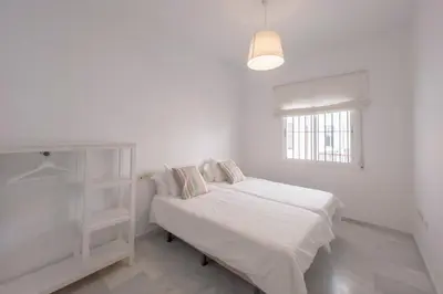 a white bedroom with a bed and a window at Apartamento completamente nuevo en pleno centro del Puerto in El Puerto de Santa María
