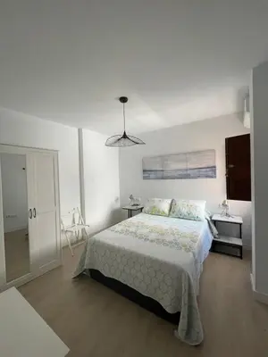 a white bedroom with a bed and a window at Luz de la Caleta in Cádiz