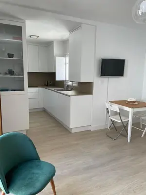 a kitchen with a green chair and a table at Luz de la Caleta in Cádiz