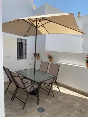 a glass table with two chairs and an umbrella at Prim 14 by 7Escalones in Rota
