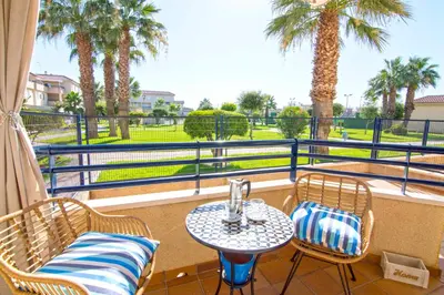 a balcony with a table and chairs and palm trees at Aires de Bajo de Guía, Apartamentos Living Sur in Sanlúcar de Barrameda