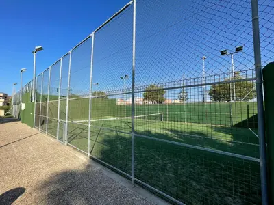 a chain link fence with a soccer field behind it at Aires de Bajo de Guía, Apartamentos Living Sur in Sanlúcar de Barrameda