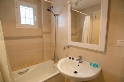 a bathroom with a sink and a mirror and a tub at Aires de Bajo de Guía, Apartamentos Living Sur in Sanlúcar de Barrameda