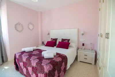a bedroom with a large bed with red pillows at Aires de Bajo de Guía, Apartamentos Living Sur in Sanlúcar de Barrameda