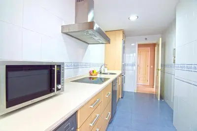 a large kitchen with a sink and a microwave at Aires de Bajo de Guía, Apartamentos Living Sur in Sanlúcar de Barrameda