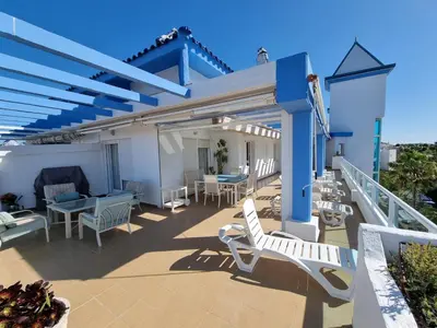 a patio with white chairs and tables on a balcony at Ático en Costa Ballena con Barbacoa, Aire Acondicionado y WIFI in Costa Ballena