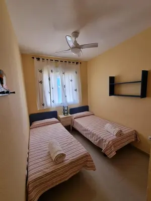 two beds in a room with a ceiling fan at Ático en Costa Ballena con Barbacoa, Aire Acondicionado y WIFI in Costa Ballena