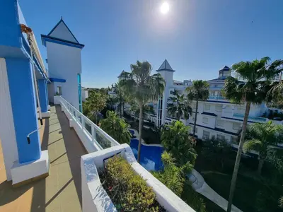 a balcony with palm trees and a building at Ático en Costa Ballena con Barbacoa, Aire Acondicionado y WIFI in Costa Ballena